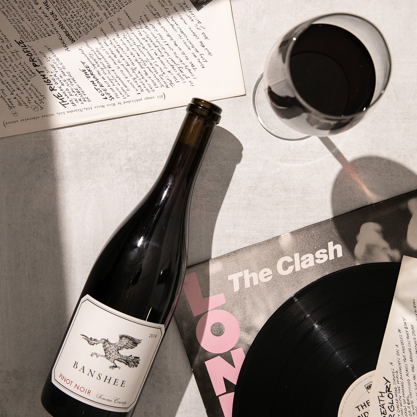 bottle of wine laying over a clash album